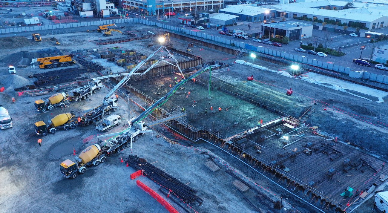 Trucks pouring concrete at the metro sports facility site.